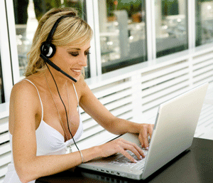 Lady with a headset and mike in front of her laptop attending an audio conference call.